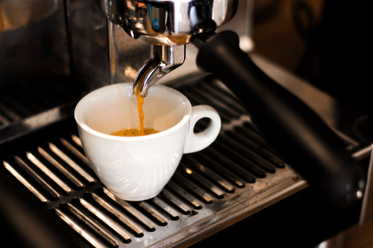 Espresso läuft aus der Siebträgermaschine in eine weiße Tasse
